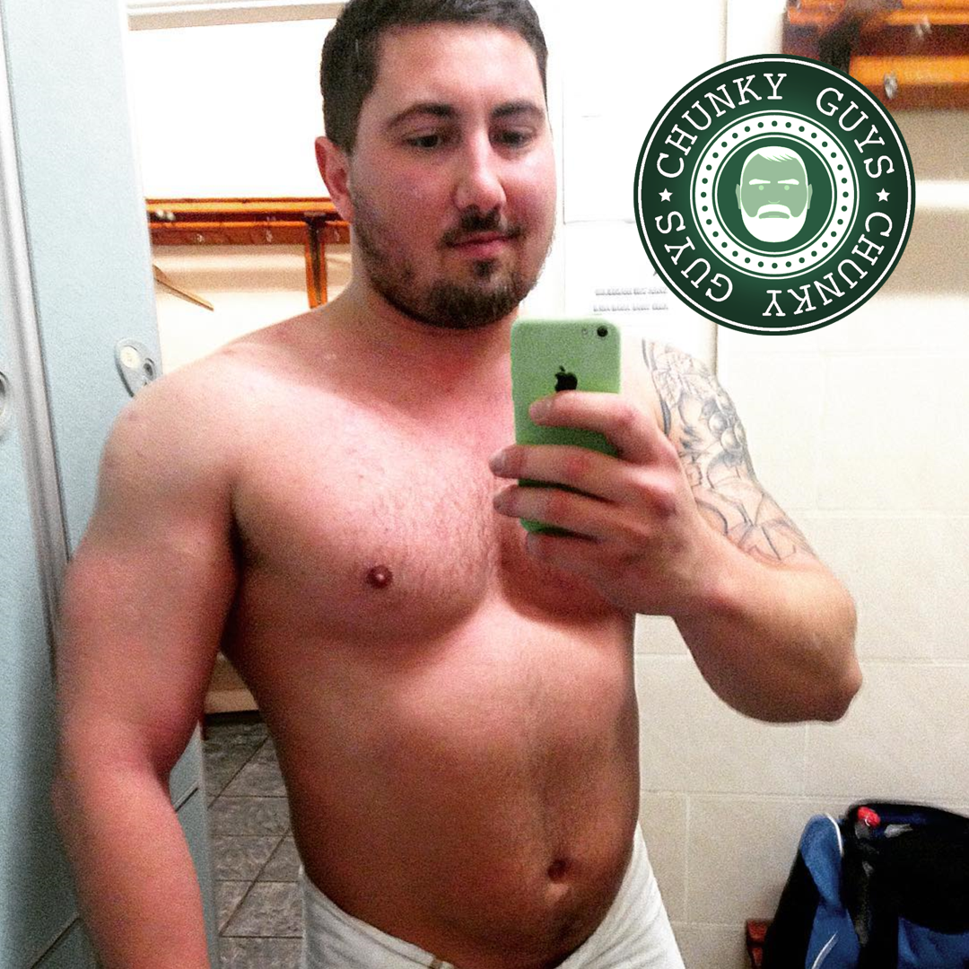Young muscular cubby guy with beard and dark hair standing in a changing room with a white towel around his waist