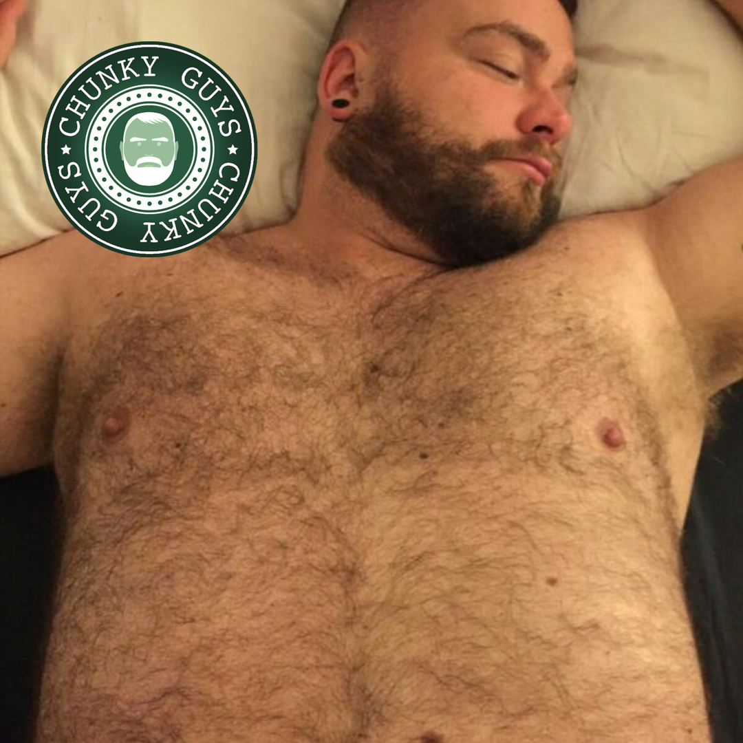 Bearded hairy cub with tunnels in his ears lying down