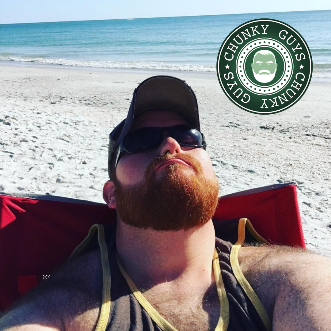Ginger bearded bear sunbathing on the beach
